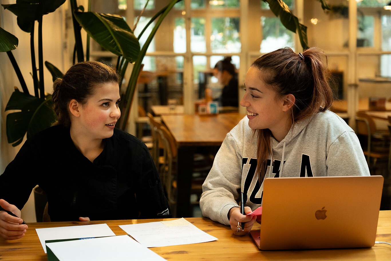 [Translate to English:] Sozialpädagogin Annalena Pfammatter von Blindspot im Coaching mit einer Auszubildenden mit Beeinträchtigung im Restaurant Fabrique28.